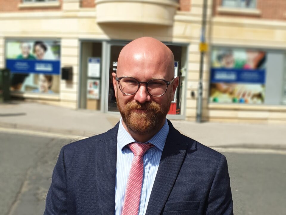 Photo shows Scott wearing a suit, stood with MySight York in the background.