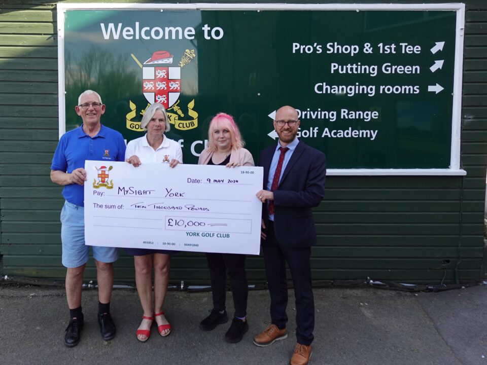 Four people (two representing York Golf Club, two representing MySight York) holding a large cheque for £10,000 in front of a green York Golf Club sign.