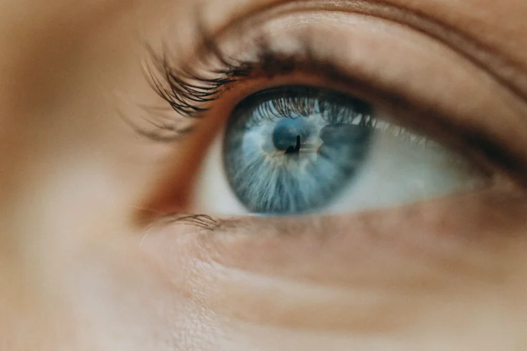 Extreme close-up of a person's blue eye, looking up and to the side, with lashes and the surrounding skin softly out of focus.