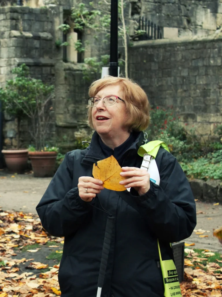 A member during a sensory walk, holding an autumn leaf with both hands.