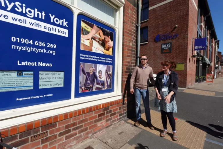 A man and a woman walking past the MySight York office window.